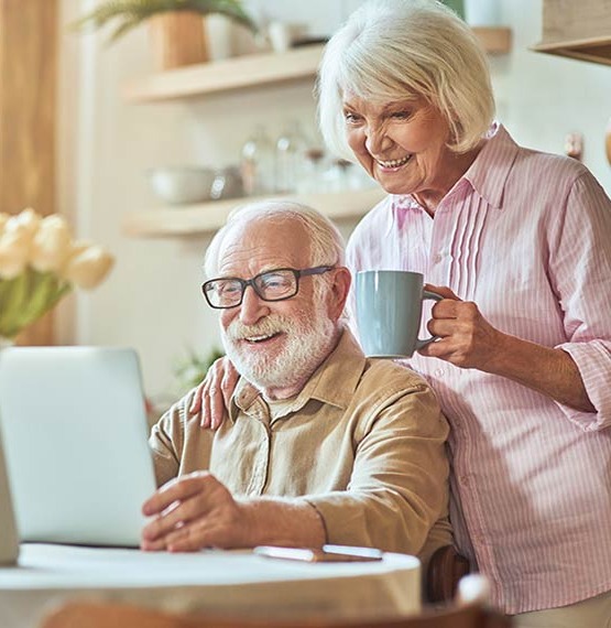 elderly couple smiling looking at laptop 