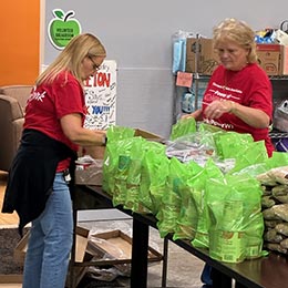 two AbbyBank employees volunteering filling food bags for St. Joseph Food Program in Menasha during AbbyBank's volunteer day in October 2025