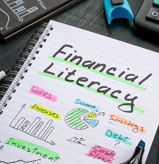 notebook open on desk with the word Financial Literacy written in and some financial literacy related items written underneath with notes highlighted