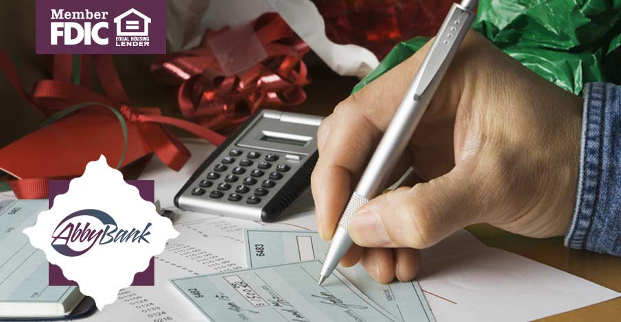 person writing out checks with calculator and papers nearby