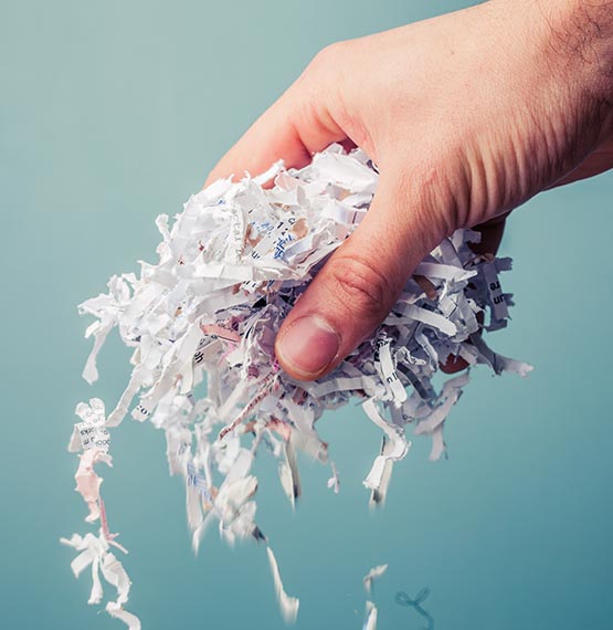 male hand holding shredded paper over gradient blue background