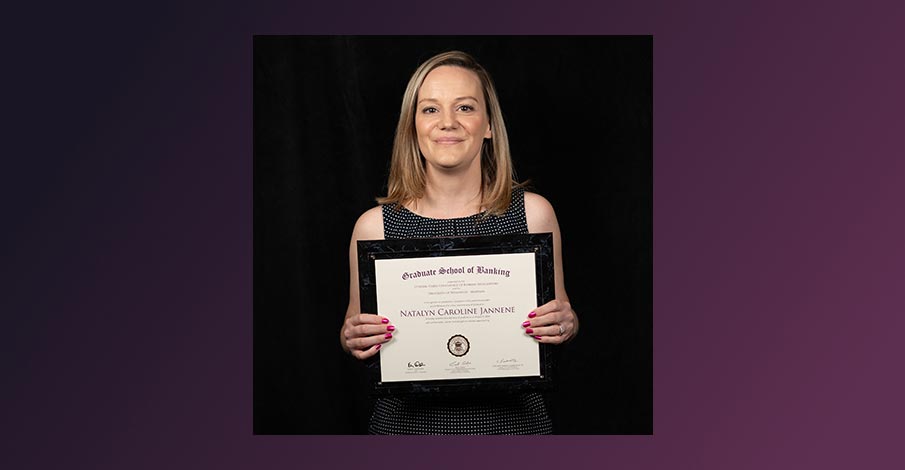 Natalyn Jannene, AVP of Marketing at AbbyBank, posing with Graduate School of Banking diploma on purple gradient background