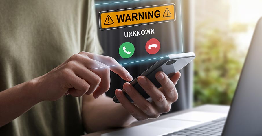 person on laptop receiving an unknown phone call with a warning message to prevent scams