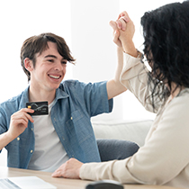 teen boy high-fiving his mom while holding up a debit card