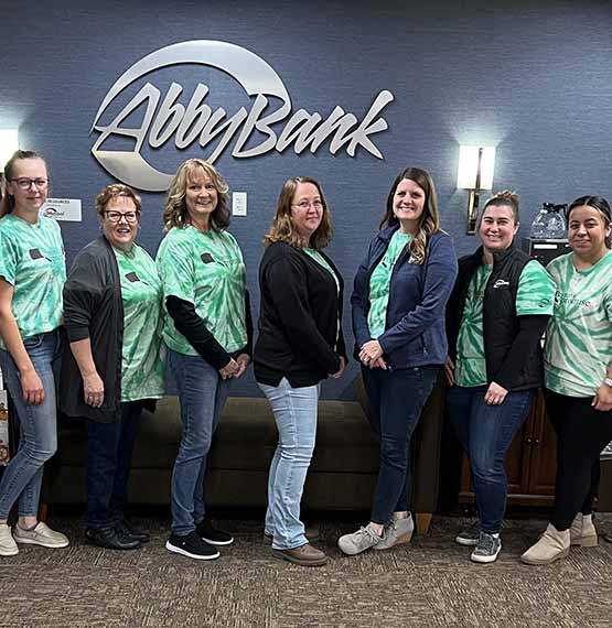 group of AbbyBank employees in Medford wearing Peyton's Promise shirts, posing in front of AbbyBank sign for a picture during a bank wide Peyton's Promise donation day 