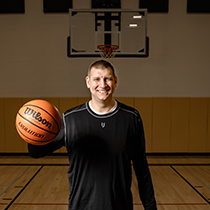 Brian Butch holding a basketball in his hand with basketball hoop in the background